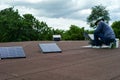 Rear view of worker cleaning the surface of solar cell on the roof