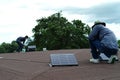 Closeup the solar cell on the roof with motion blurred worker fixing and sealing the surface