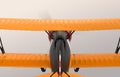 Rear view of yellow and black biplane flying in the sky Royalty Free Stock Photo