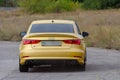 Rear view Yellow sedan drives at high speed on a paved road. Aud