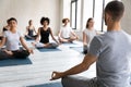 Rear view yoga trainer and group of people meditating indoors