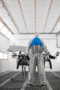 Rear view on young adult auto mechanic holding machine for polishing and cleaning, painting of cars