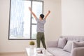 Rear view of a young Asia man stretching his arms near window at Royalty Free Stock Photo