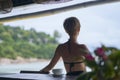 Rear view of young Asian beauty sitting, relaxing at beach bar in vacation Royalty Free Stock Photo