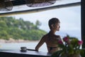 Rear view of young Asian beauty sitting, relaxing at beach bar in vacation