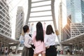 Rear view young asian businesswoman group in business formal wear, they raising hands and pointing something with urban view