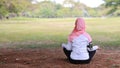 Rear view young asian muslim woman sitting on grass, enjoying meditation. Peaceful girl in sportswear with hijab practice yoga in