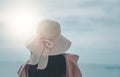 Rear view young Asian woman standing of happy attractive with hands holding sun hat up, sunny day, summer sea, blue sky background