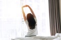 Rear view of young Asian woman stretching after wake up with sunlight in the morning in bedroom at home or hotel. Closeup Royalty Free Stock Photo