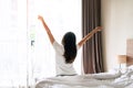 Rear view of young Asian woman stretching after wake up with sunlight in the morning in bedroom at home or hotel. Closeup, copy Royalty Free Stock Photo
