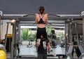 Rear view of a Young attractive woman pulling up on a Chin up bar exercise in a Gym.