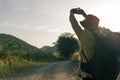 Rear view of a young backpacker male stretching his arm while hiking into the mountains in the evening sunset during summer. Royalty Free Stock Photo