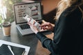 Rear view. Young businesswoman working on smartphone with graphs, charts, diagrams on screen. Online marketing,education