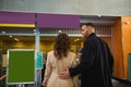 Rear view of a young couple of business partners standing at the check-in counter while waiting for check-in, customs and passport Royalty Free Stock Photo