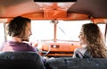 A rear view of young couple on a roadtrip through countryside, driving minivan. Royalty Free Stock Photo