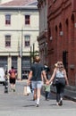 Rear view of a young couple walking down the street holding hands and shopping bags Royalty Free Stock Photo