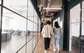 Rear view of young couple walking to office along walkway in open plan building Royalty Free Stock Photo