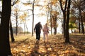 Rear view of young family with one small children walking in autumn nature. Walk in the autumn park. Royalty Free Stock Photo