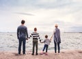 Rear view of young family with two small children standing outdoors on beach. Royalty Free Stock Photo