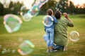 Rear view of young father and his cute little girl having fun while blowing soap bubbles in the park, daughter and dad Royalty Free Stock Photo