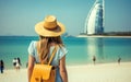 Rear view Young girl with backpack in a hat standing looks into the Burj Al Arab, United Arab Emirates