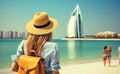 Rear view Young girl with backpack in a hat standing looks into the Burj Al Arab, United Arab Emirates