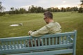 Rear view of a young handsome man sitting on the wooden bench in park and using digital tablet Royalty Free Stock Photo