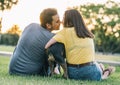 Rear view of young happy couple kissing with their dog in park Royalty Free Stock Photo