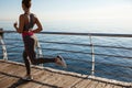 Rear view of young healthy woman workout near the sea. Girl jogging alone, training on seaside promenade Royalty Free Stock Photo