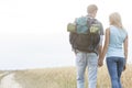 Rear view of young hiking couple holding hands while walking in countryside