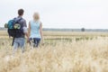 Rear view of young hiking couple walking through field