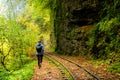 Rear view of a young hiking tourist girl enjoying amazing beauty of nature. Excursion on old narrow railroad in mountain region