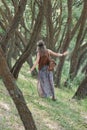 Rear view.young hippie woman standing among the trees in the forest Royalty Free Stock Photo