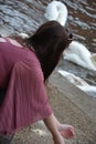 Rear view of a young lady leaning over to feed swans / ducks