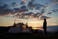 Rear view of young lady standing on top of mountain near camping at sunrise enjoying the view Royalty Free Stock Photo