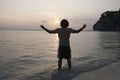 Rear view of young man with arms outstretched on beach at sunset