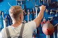 Rear view of a man choosing an useful tool during work in a repair shop