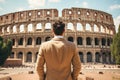 Rear view of young man looking at Colosseum in Rome, Italy, Male tourist standing in front of a sandy beach and watching the sea, Royalty Free Stock Photo