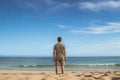 Rear view of young man standing on beach and looking at sea, Male tourist standing in front of a sandy beach and watching the sea Royalty Free Stock Photo