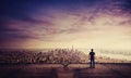 Rear view of young man standing on the rooftop of a skyscraper watching sunset over the big city horizon. Businessman on the roof Royalty Free Stock Photo