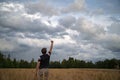 Rear view of a young man standing victorious in the middle of beautiful golden wheat field