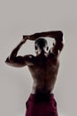 Rear view of a young muscular african american bodybuilder raising his arms while posing shirtless  over grey Royalty Free Stock Photo