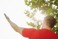 Rear view of young muscular man stretching by a tree, hand and arm raised towards the sky and the sun in Beijing, China Royalty Free Stock Photo