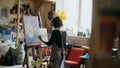 Rear view of Young painter girl in apron painting still life picture on canvas in art-class