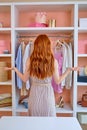 Rear view on young redhead Stressed woman standing in front of wardrobe full of clothes Royalty Free Stock Photo