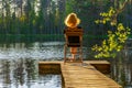 Rear view of young redhead woman sitting on chair on wooden planked footway at lake in summer evening at sunset. Beautiful girl Royalty Free Stock Photo