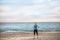 Rear view of young sporty woman runner in blue sportswear standing on the beach. Royalty Free Stock Photo