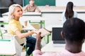 rear view of young students sharing notebook at classroom