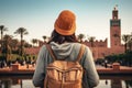 Rear view of a young woman with a backpack and a hat standing in front of the Koutoubia Mosque in Marrakesh, Morocco, rear view of Royalty Free Stock Photo