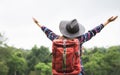 Rear view of young woman with backpack and hat, Traveler standing with raised arms and enjoying a beautiful nature Royalty Free Stock Photo